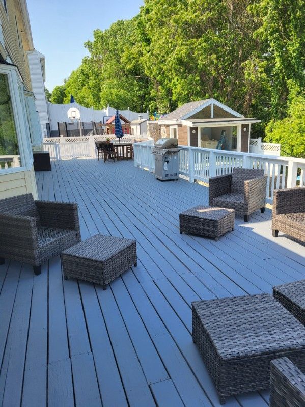 Backyard deck with wicker seating, grill, and gazebo under green trees