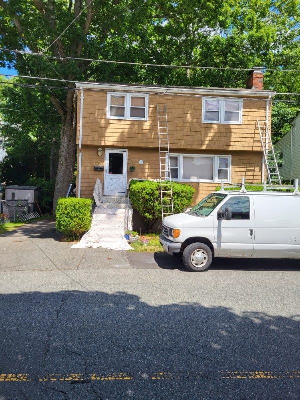 Two-story tan house with a white van parked in front and a small front yard.