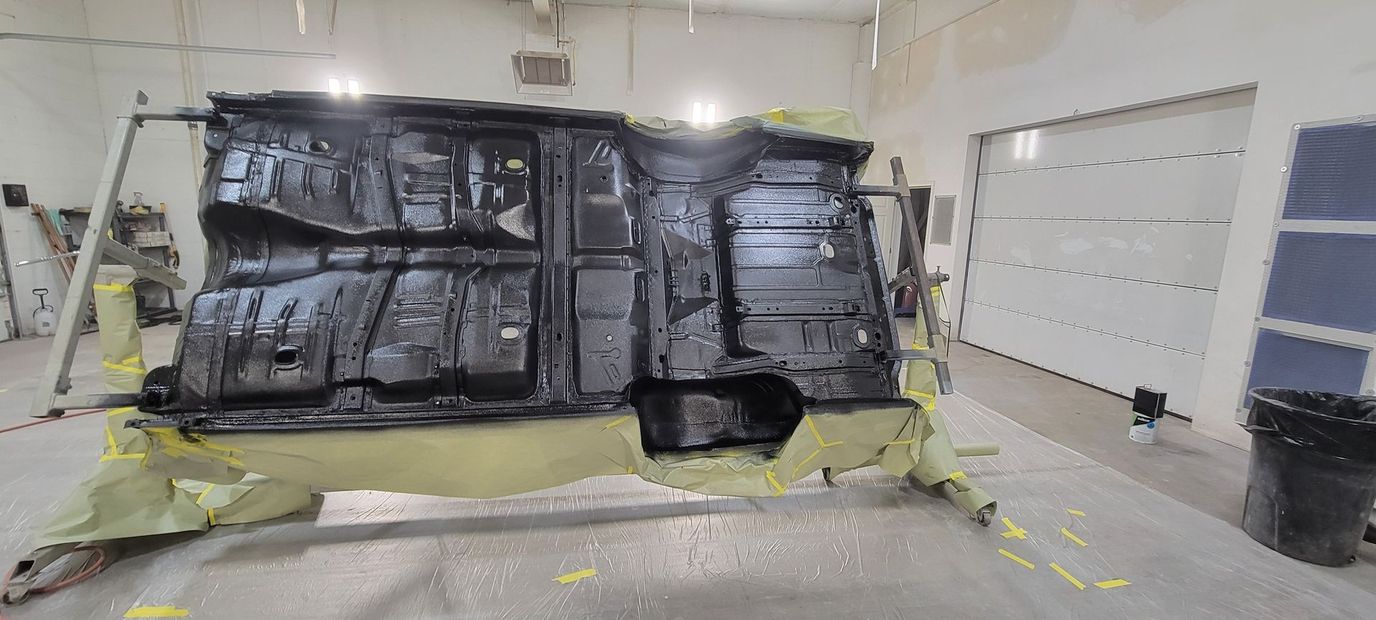 Large black tarp-covered structure in a bright room, with yellow tape and scattered equipment on the floor.