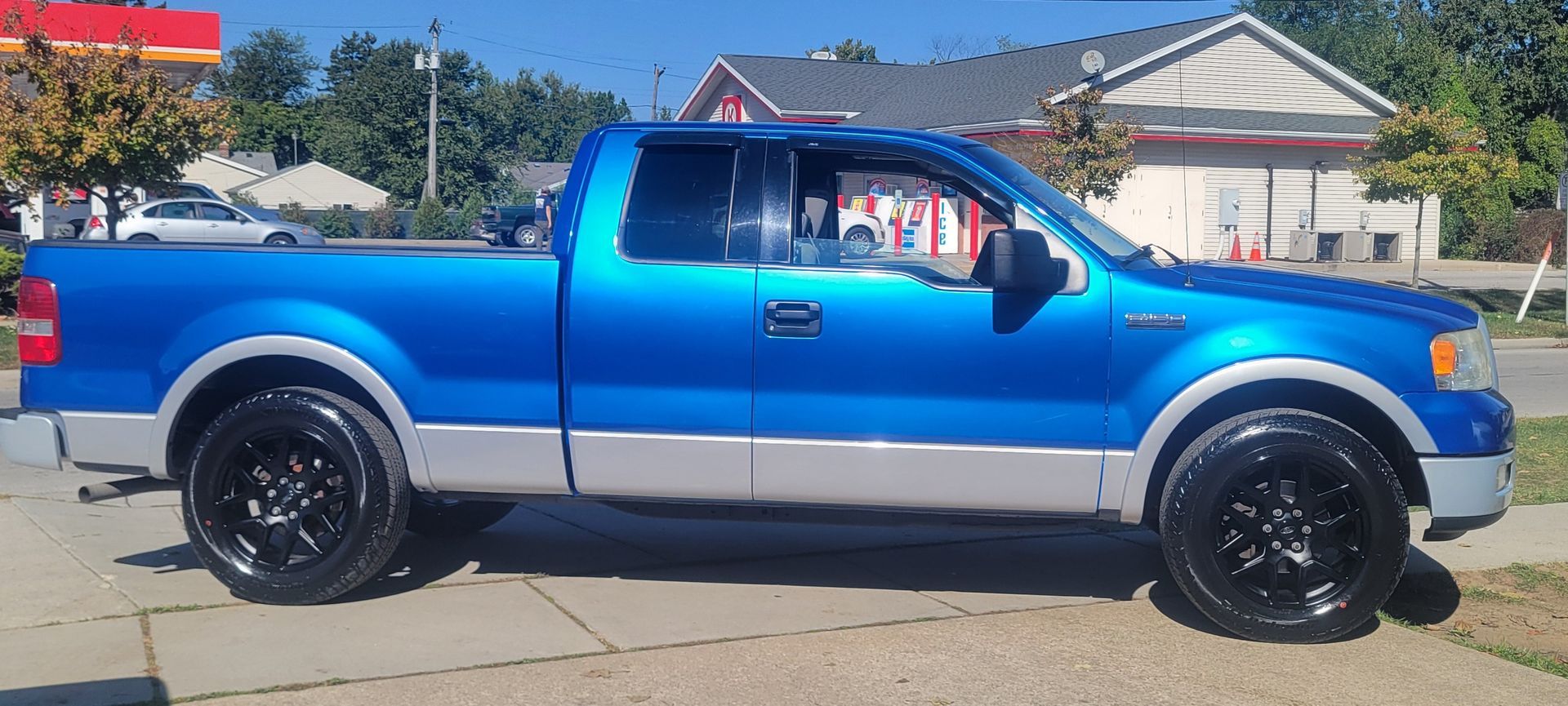 Blue and silver pickup truck parked on a sunny street, side view