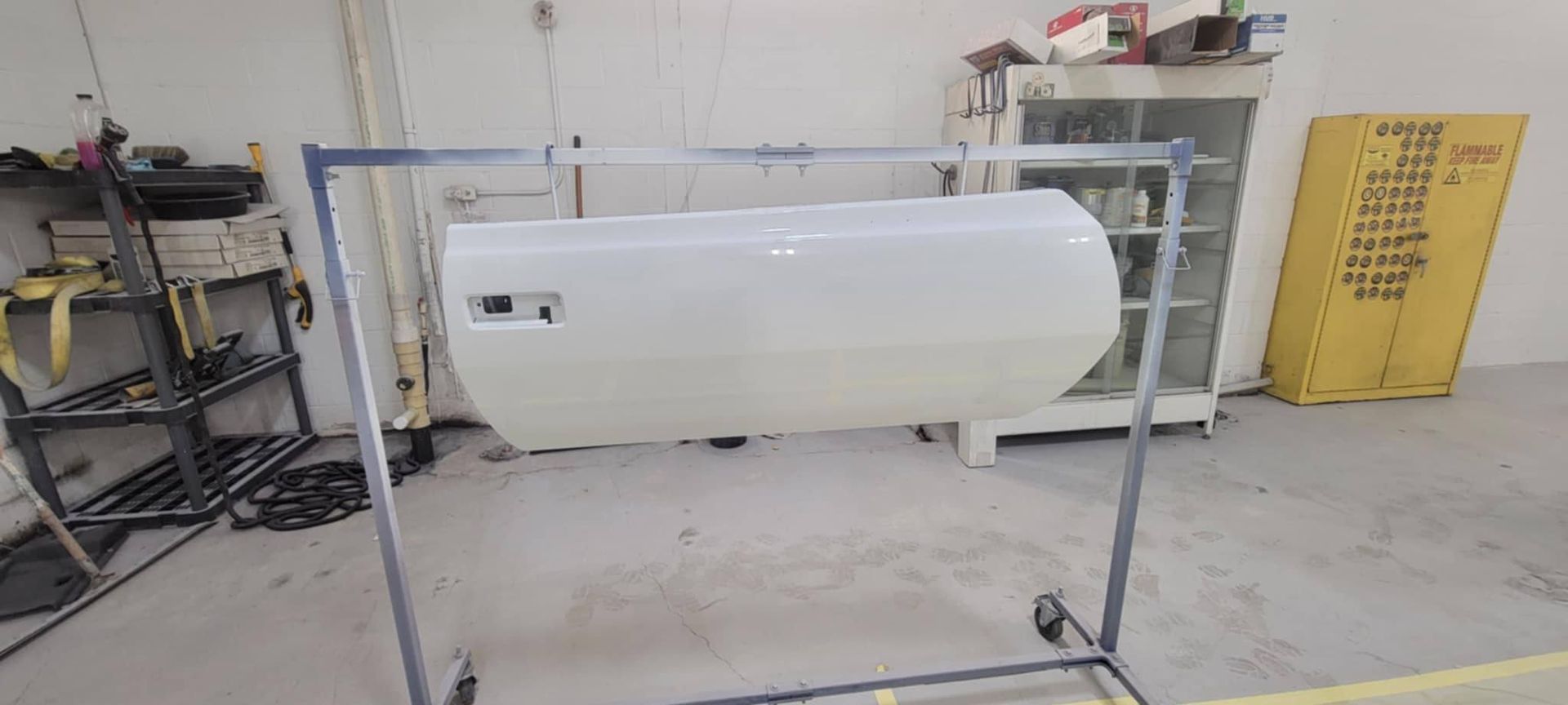 White cylindrical tank mounted on a black metal stand in an industrial workshop