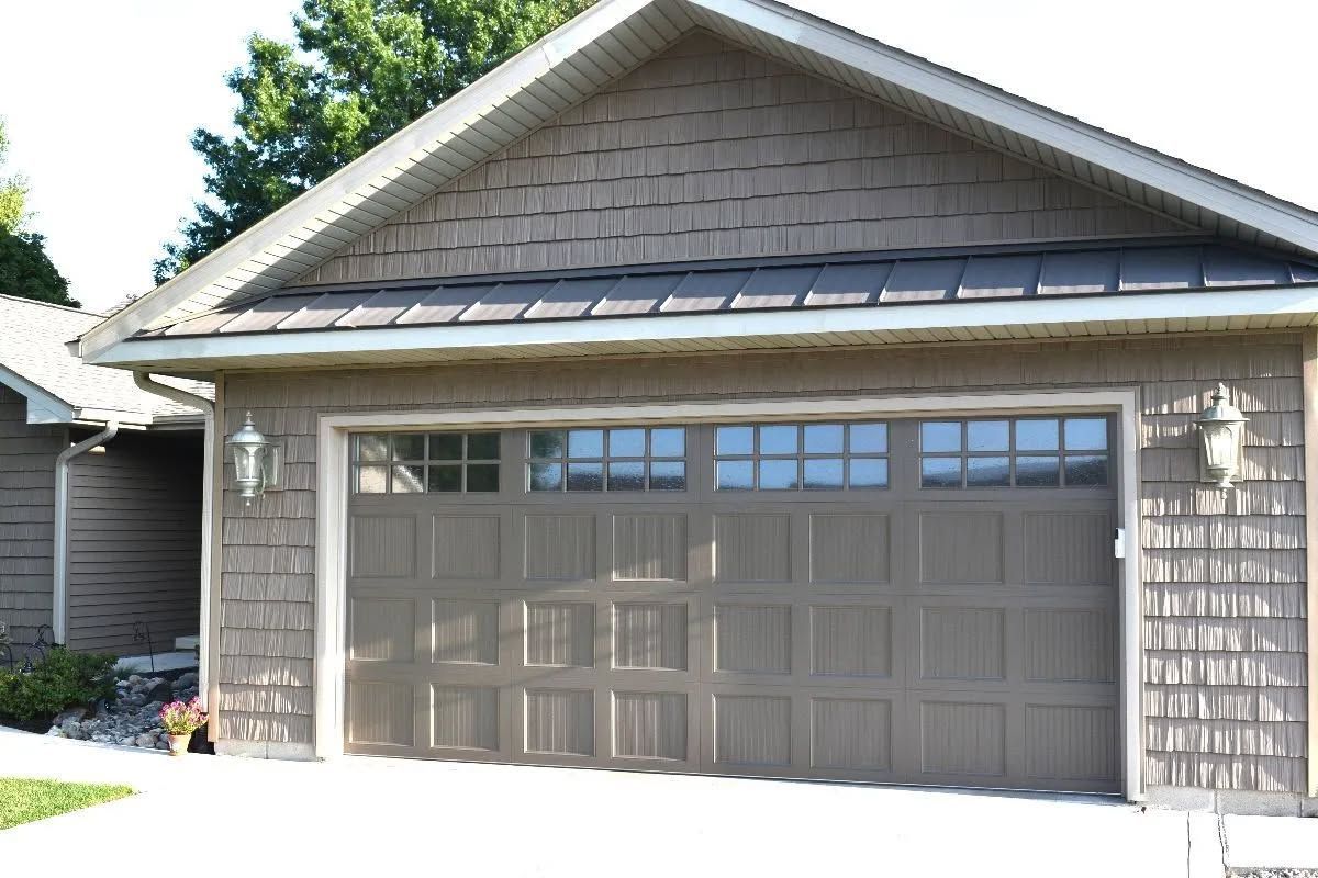Suburban house with a double garage door and gray siding in bright daylight