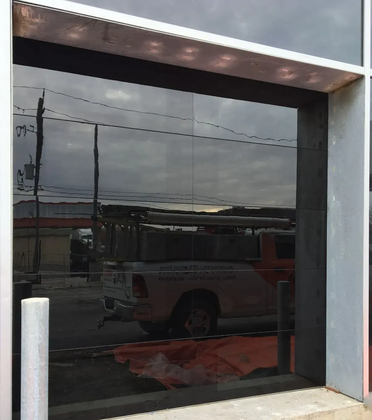 Dark reflective glass storefront window with a red van reflected outside