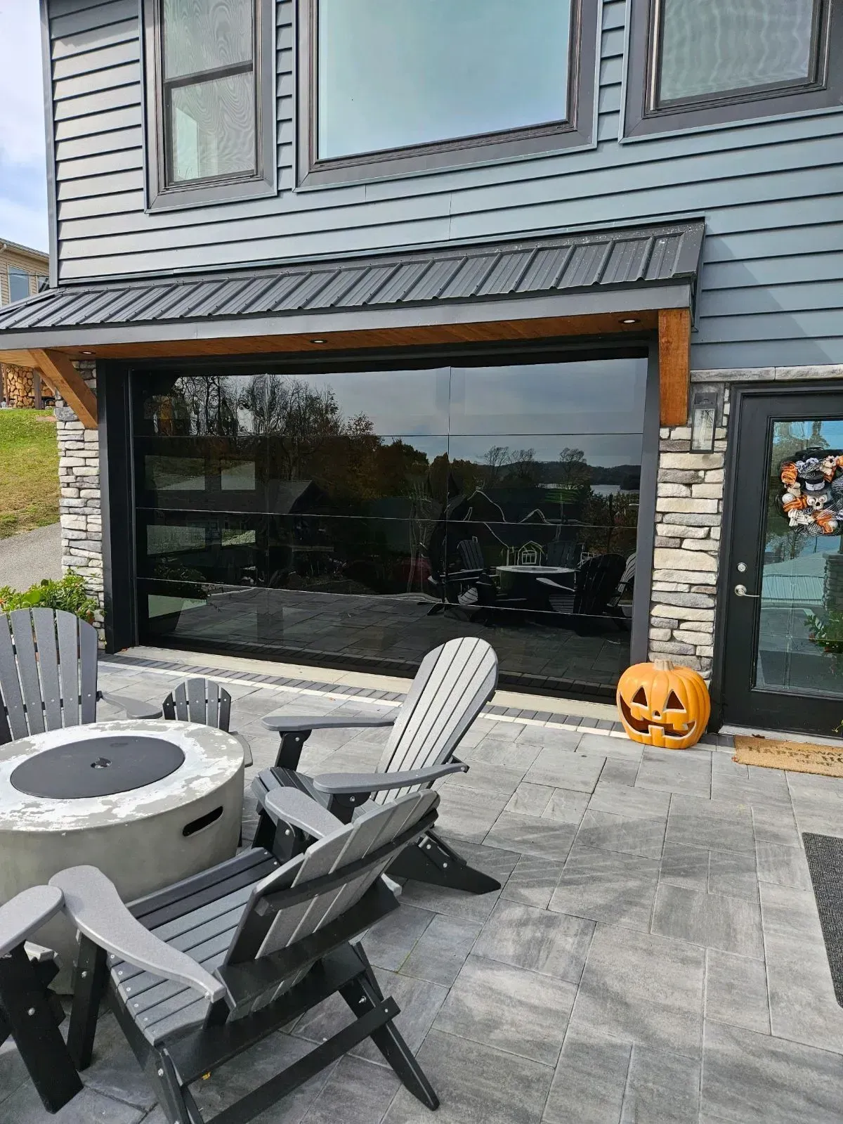 Patio with hot tub, chairs, large window, and Halloween pumpkin decoration by a house