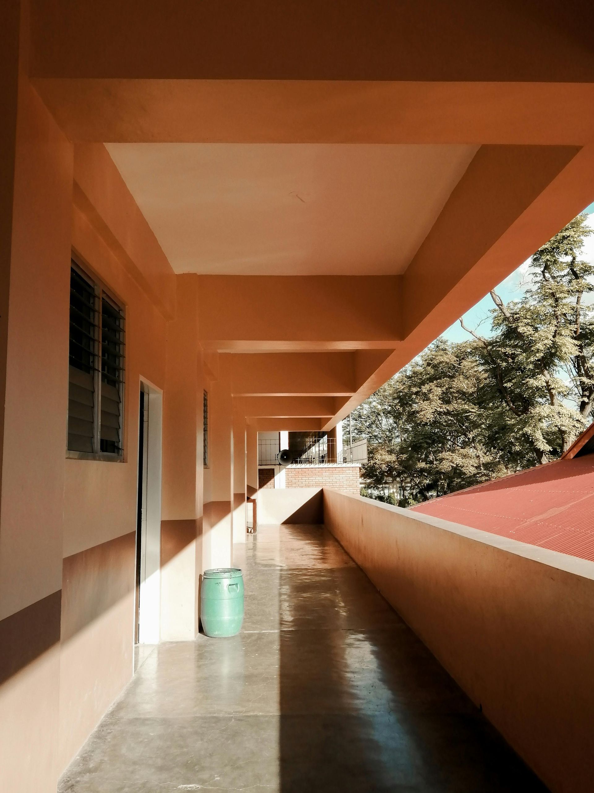 A long hallway with a green trash can in the middle