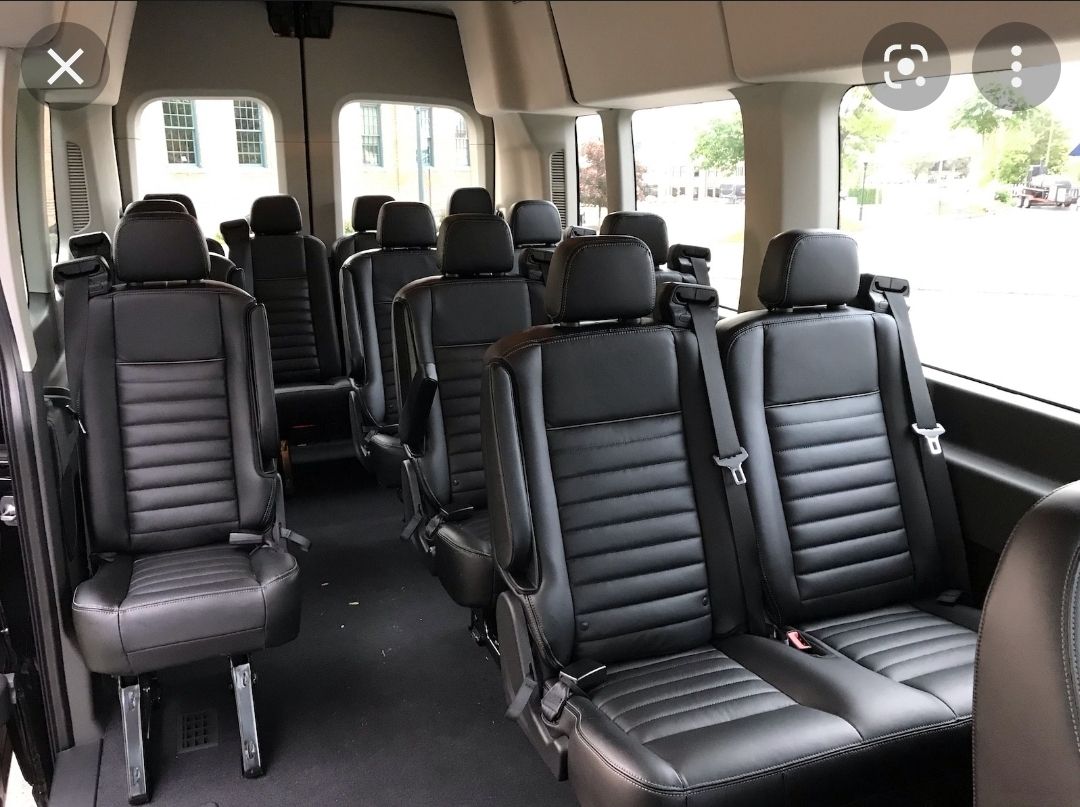 Interior of a passenger van with rows of black leather seats.