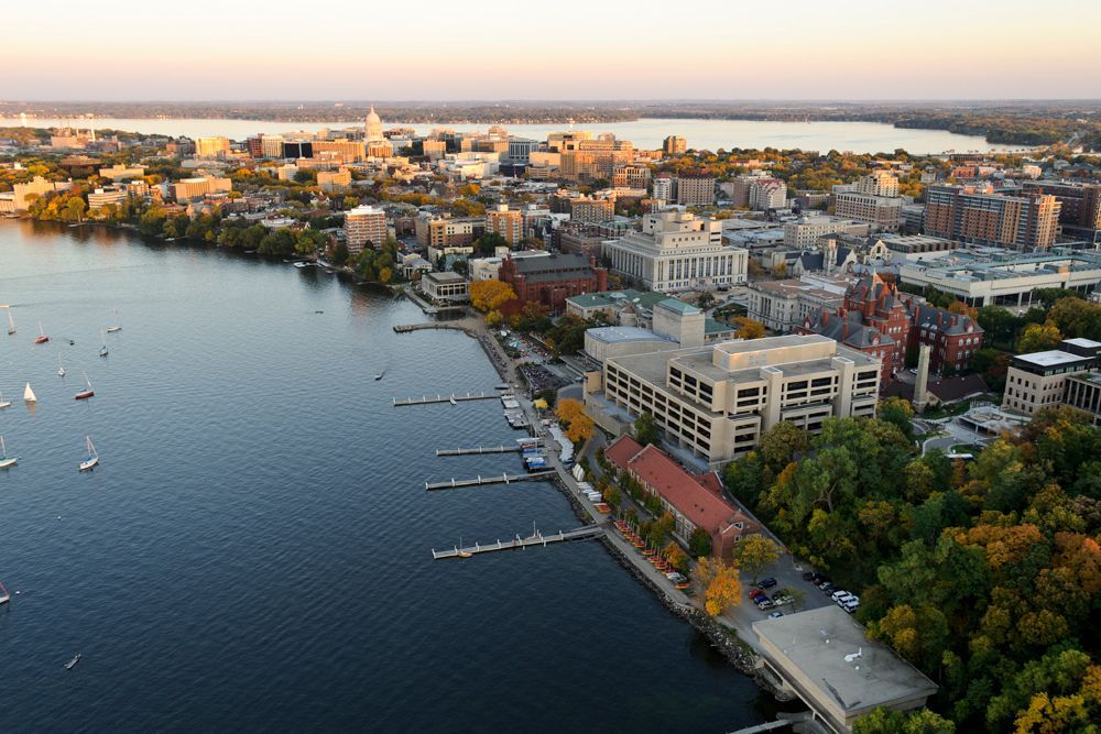 Aerial view of Madison, Wisconsin, featuring buildings, lakeshore, and sailboats. Autumn colors.