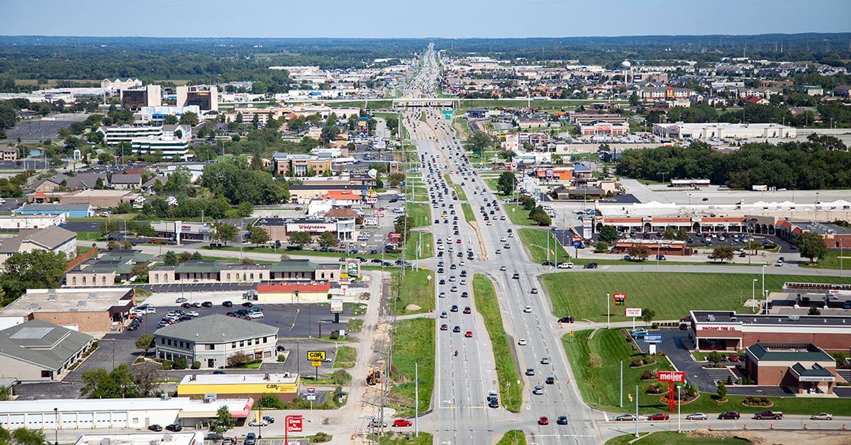 Aerial view of a wide road lined with buildings and trees, with traffic.