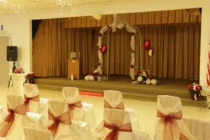 Wedding ceremony venue with decorated chairs and stage.