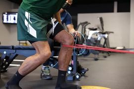 Person exercising with a red resistance band in a gym setting