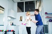 Man helping woman with arm exercise in a bright gym or therapy room