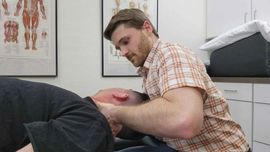 Person receiving a neck and shoulder massage from a therapist in a green shirt
