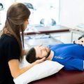 Therapist gently supports a man lying on a table during a treatment session