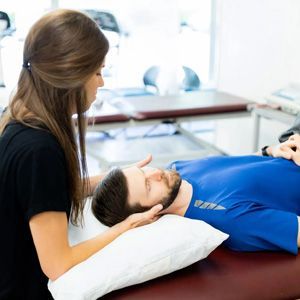 Therapist gently supports a man lying on a table during a treatment session
