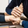 Hands holding and guiding a foot during a physical therapy stretch on a treatment table