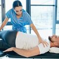 Physical therapist assisting a patient on a treatment table in a bright clinic room