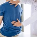 Doctor examining a patient’s back in a medical office