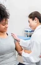 Nurse checking a patient’s arm with a blood pressure cuff in a clinic.