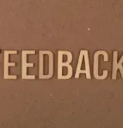 3D letters spelling “FEEDBACK” on a brown textured wall.