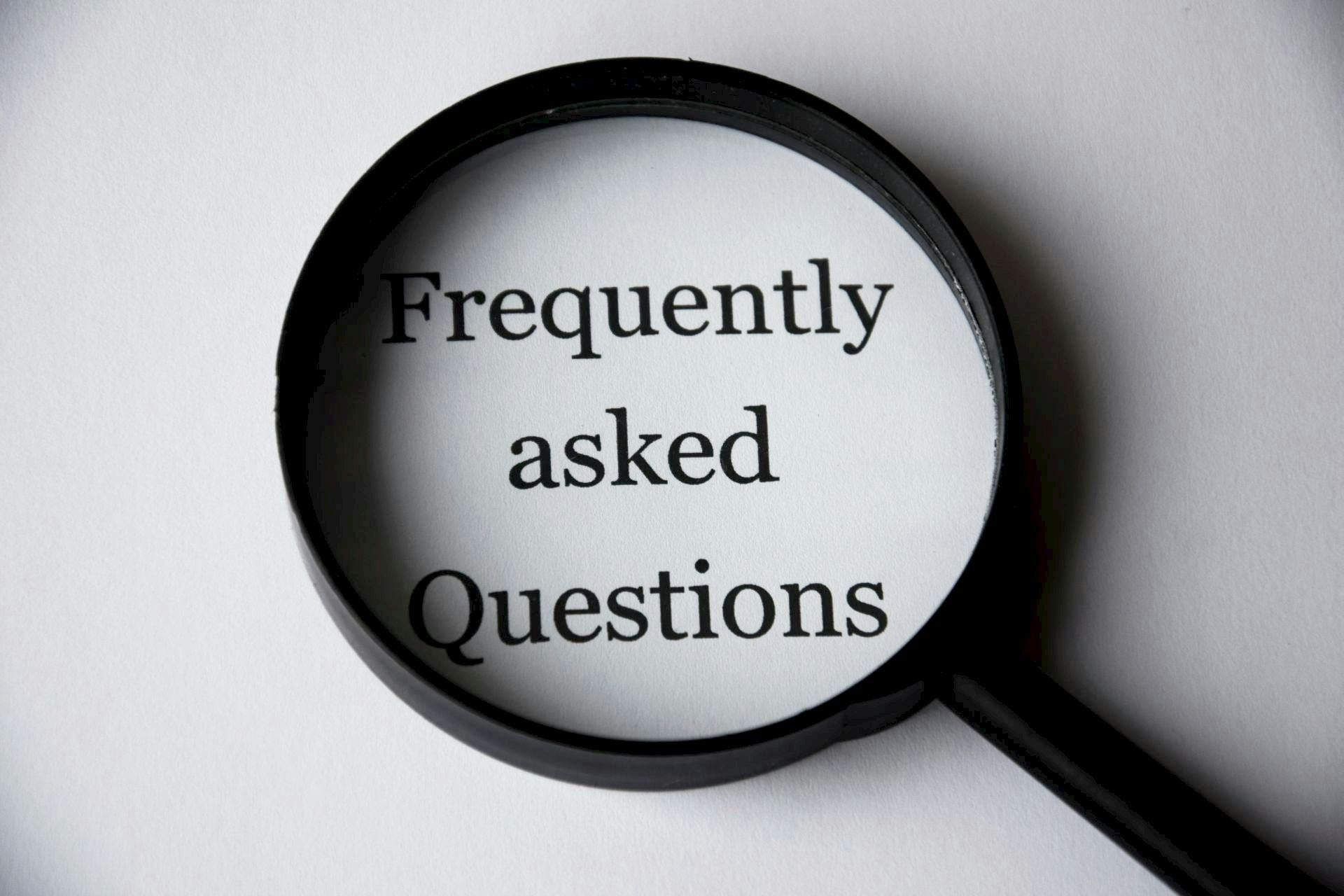 Magnifying glass over the words “Frequently asked Questions” on a gray background