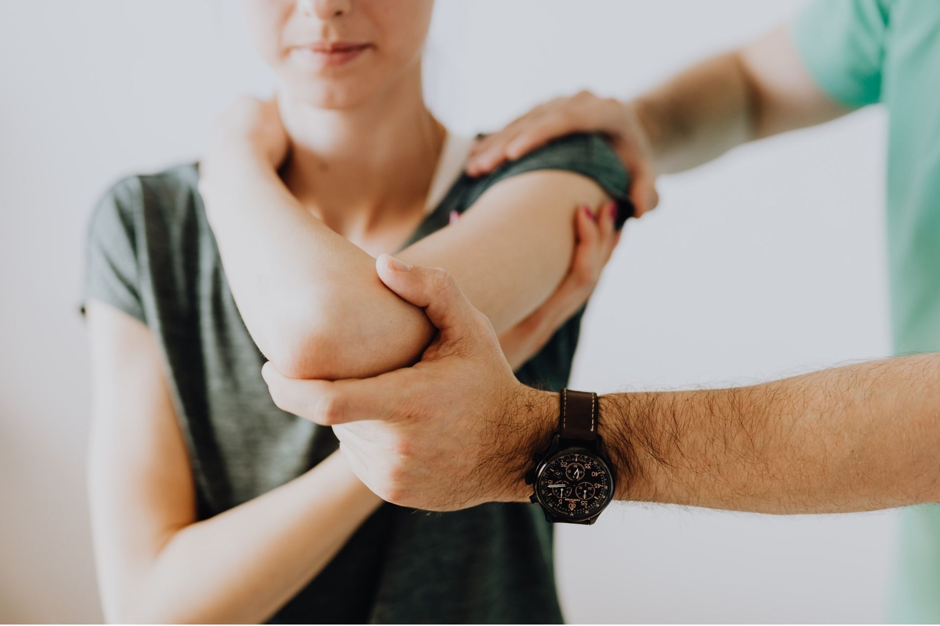 Physical therapist manipulating a patient’s elbow during rehab assessment