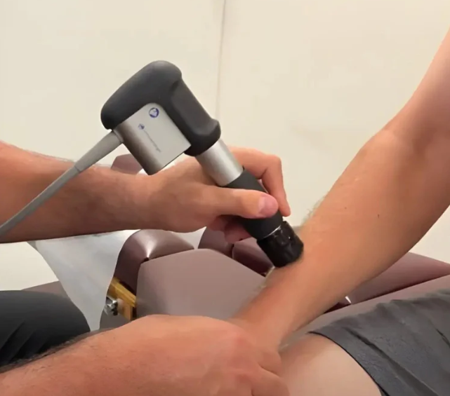 Hands holding and guiding a foot during a physical therapy stretch on a treatment table