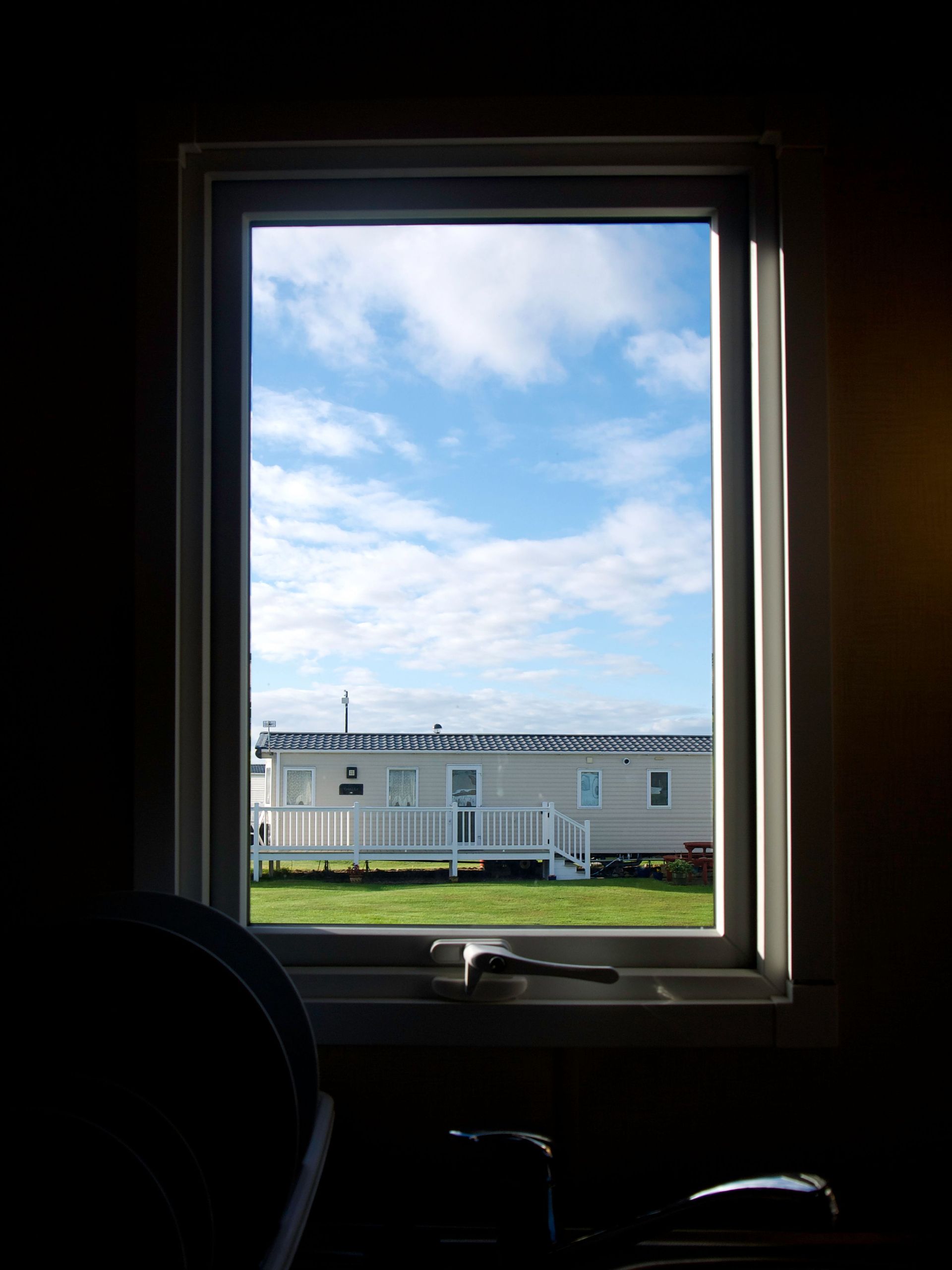 View through a window to a white mobile home and blue sky outside