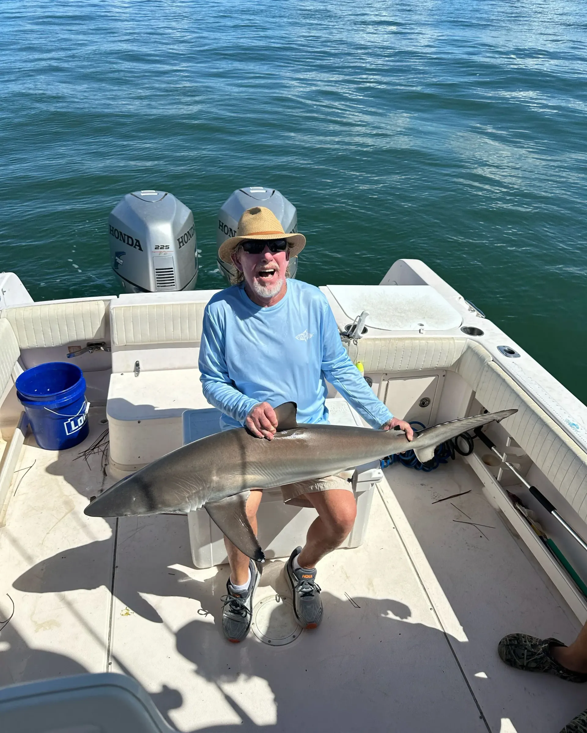 A man is sitting on a boat holding a shark