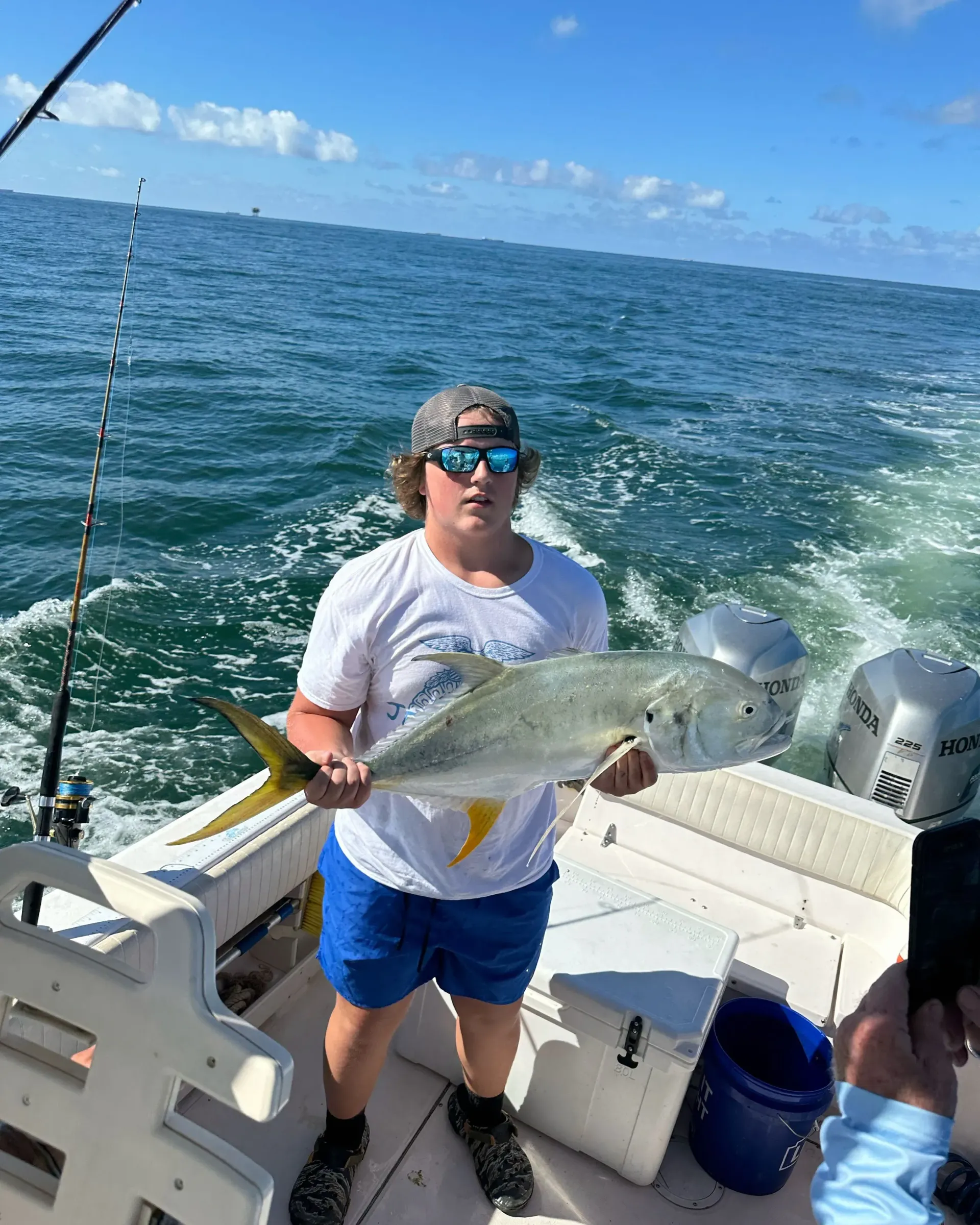 A man is holding a fish on a boat in the ocean.