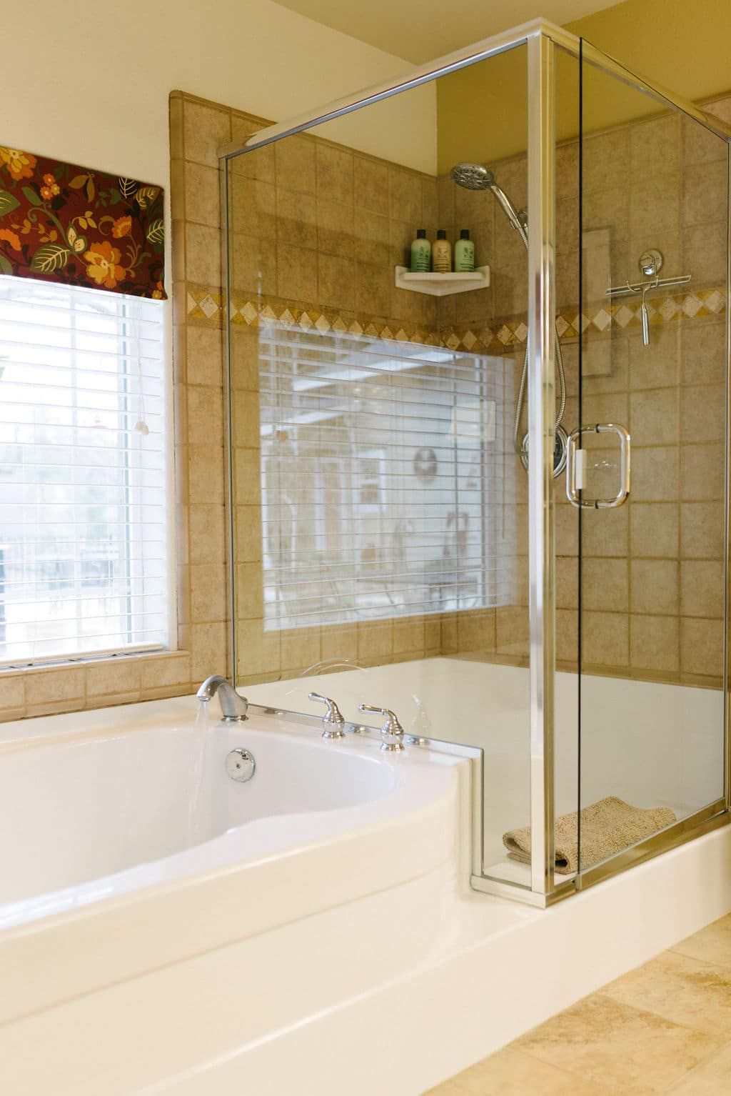 A bathroom with a tub , shower , and window.