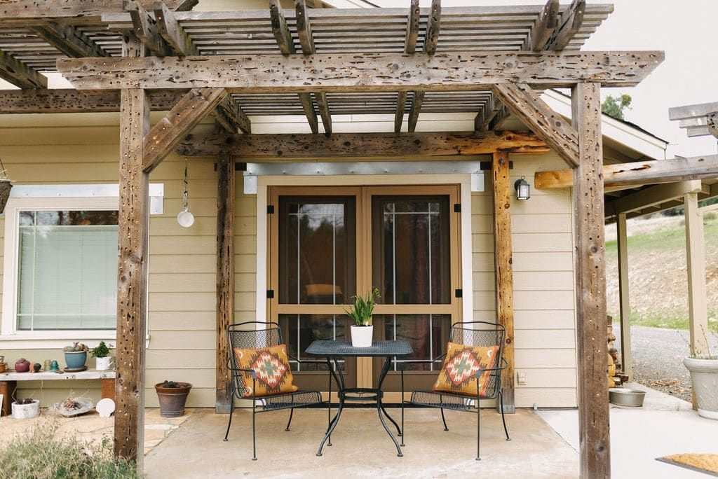 There is a table and chairs on the porch of a house.