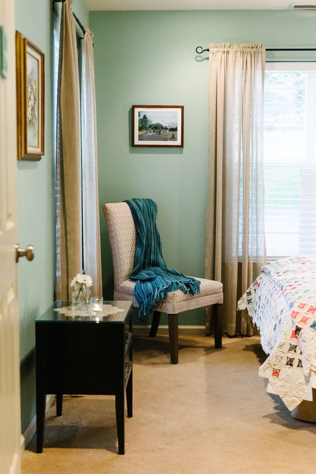 A bedroom with a bed , chair , nightstand and window.