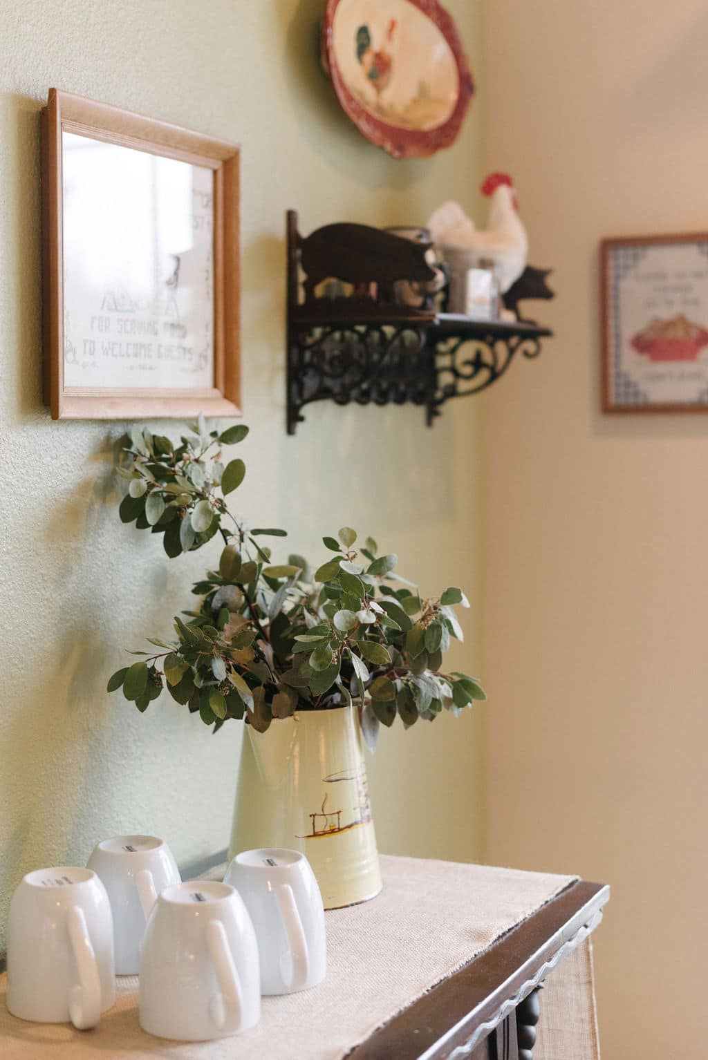A vase of flowers is sitting on a table next to a shelf with pictures on it.