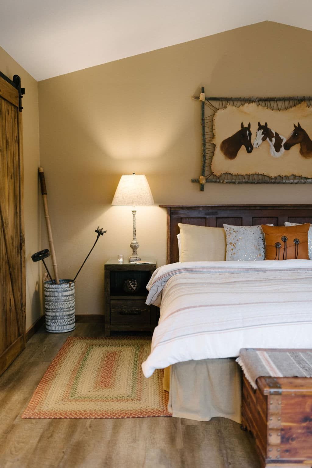 There is a picture of horses on the wall above the bed.