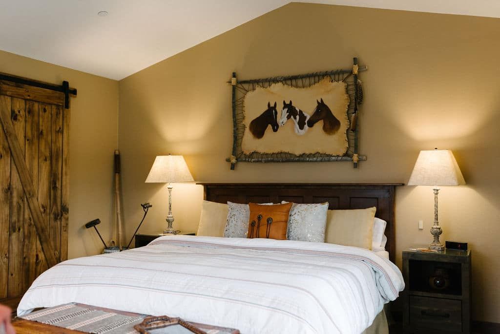 A bedroom with a king size bed and a picture of horses on the wall.