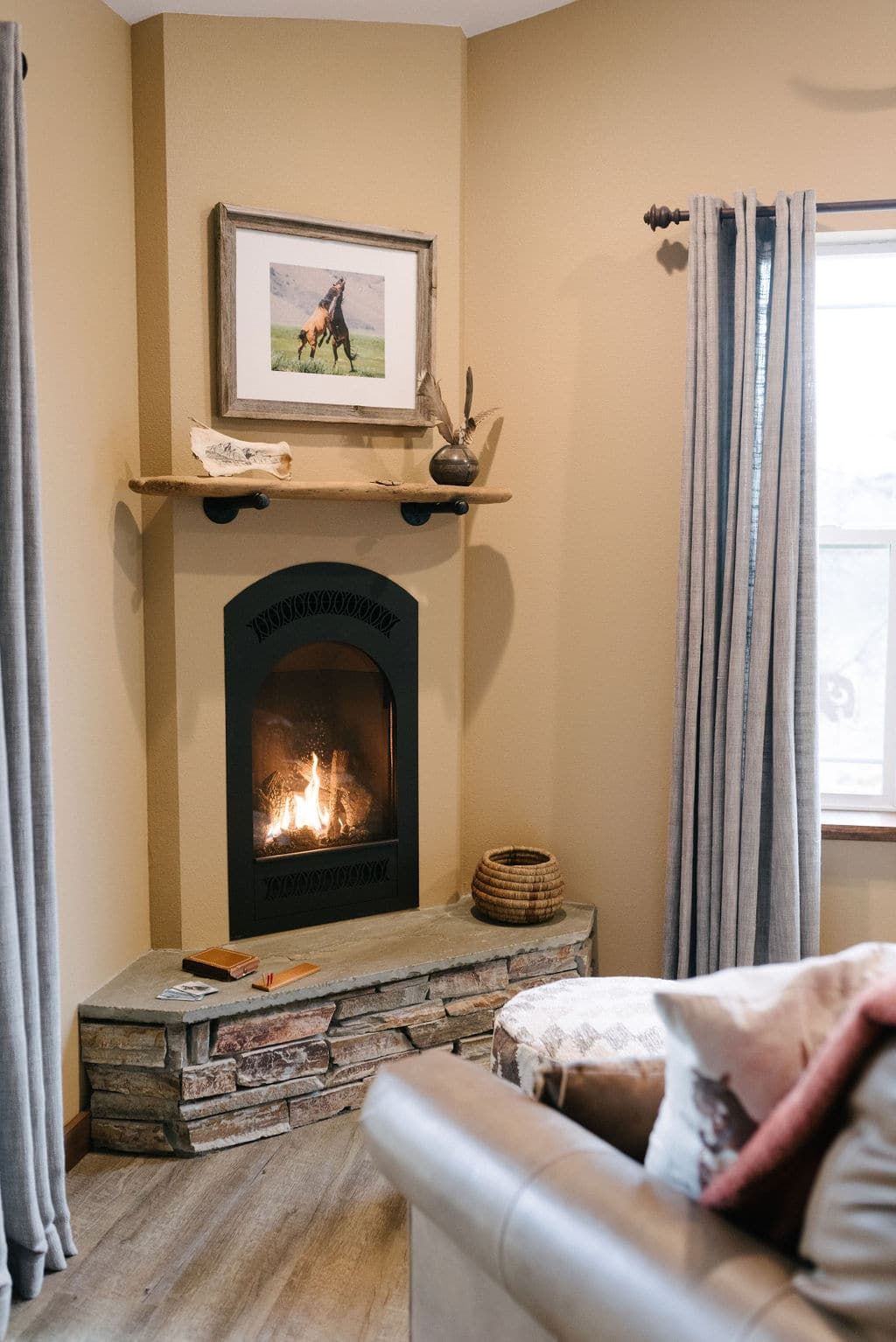 A living room with a fireplace and a picture of a horse on the mantle.