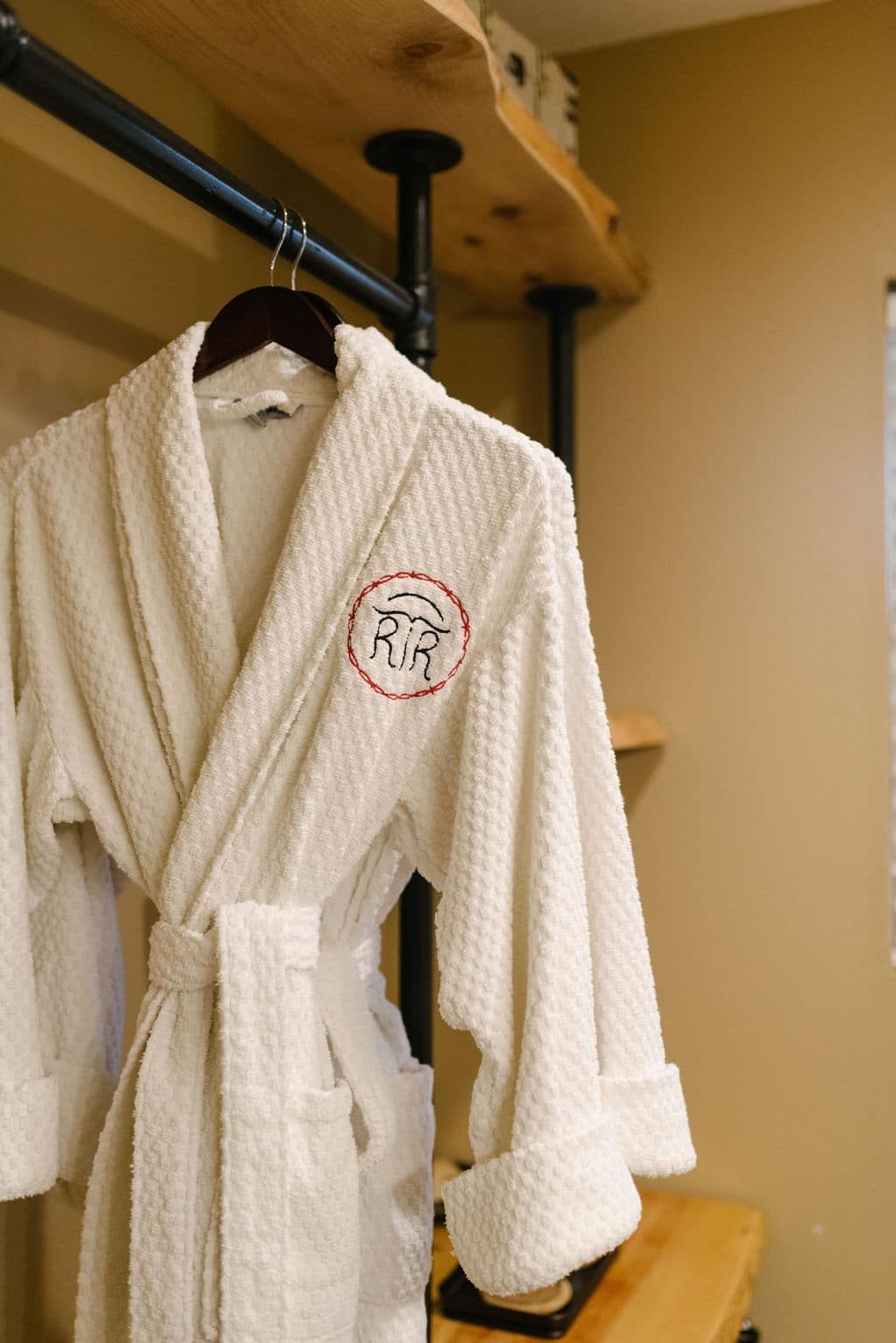 A white robe is hanging on a hanger in a room.