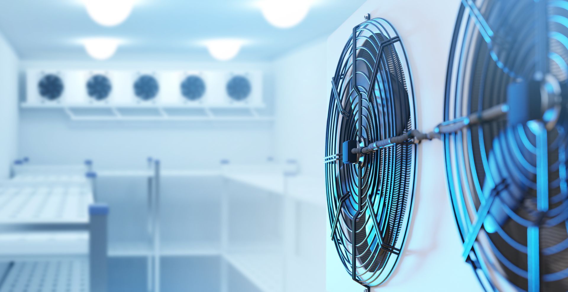Blue-lit industrial room with large wall-mounted fans and clean white equipment racks