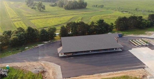 Aerial view of a large, dark-roofed building with surrounding parking on a rural landscape.