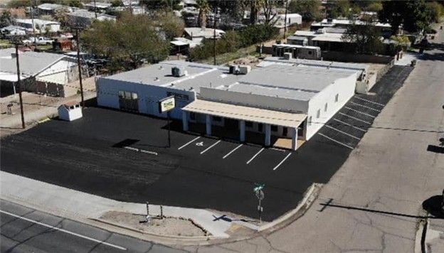 Aerial view of a commercial building with a newly paved parking lot, on a sunny day.
