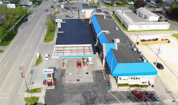 Aerial view of a gas station with a blue roof and canopy, located next to a building.