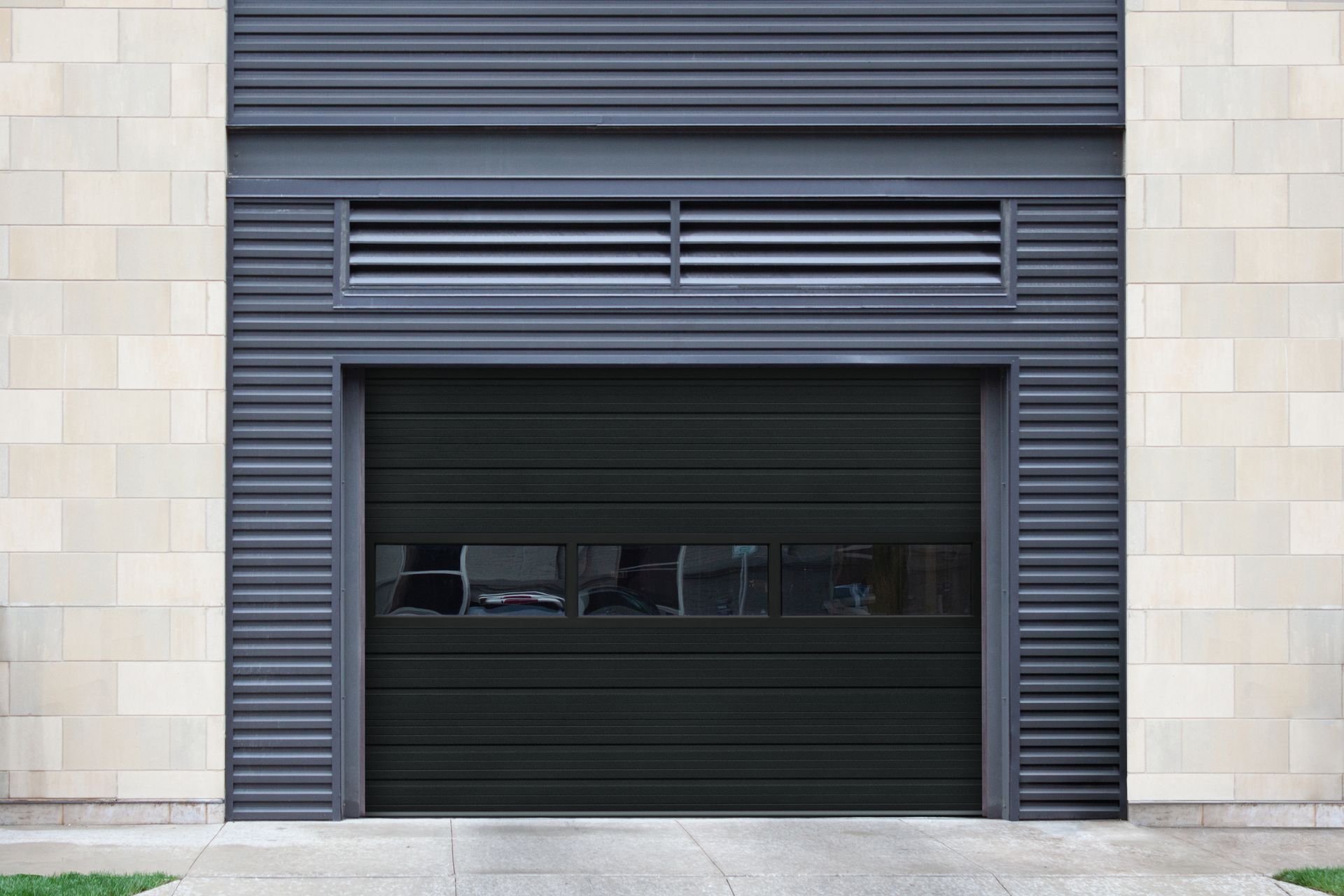 A black garage door is sitting in front of a brick building.