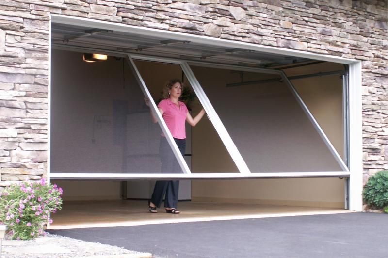 A woman in a pink shirt is standing in a garage with a screen door open.