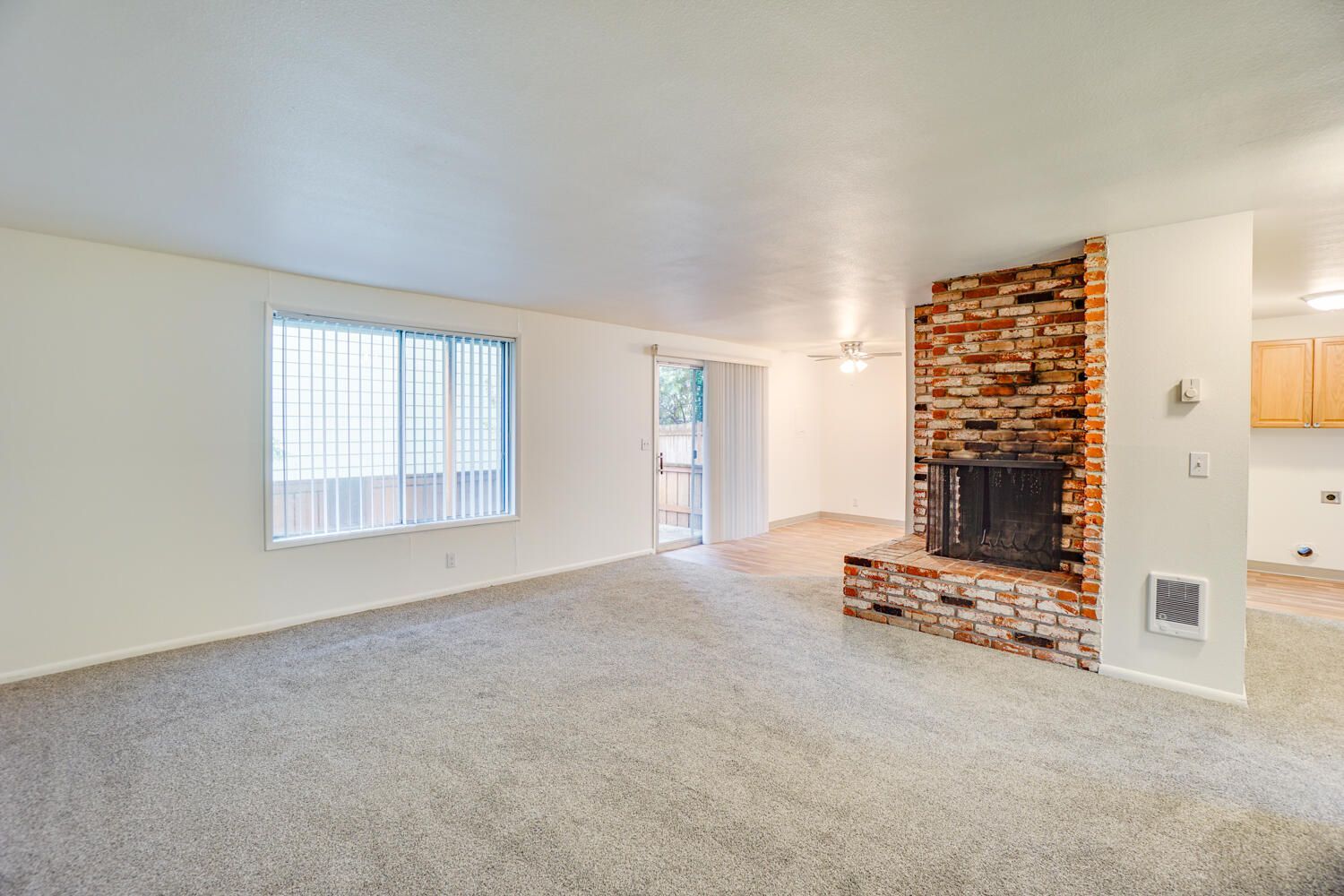 An empty living room with a fireplace and a large window.
