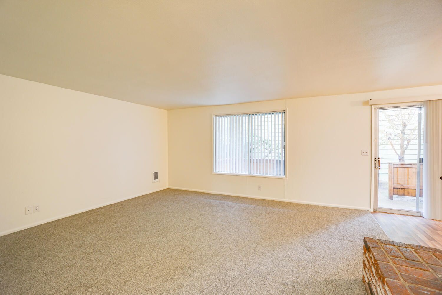 An empty living room with a sliding glass door and a fireplace.