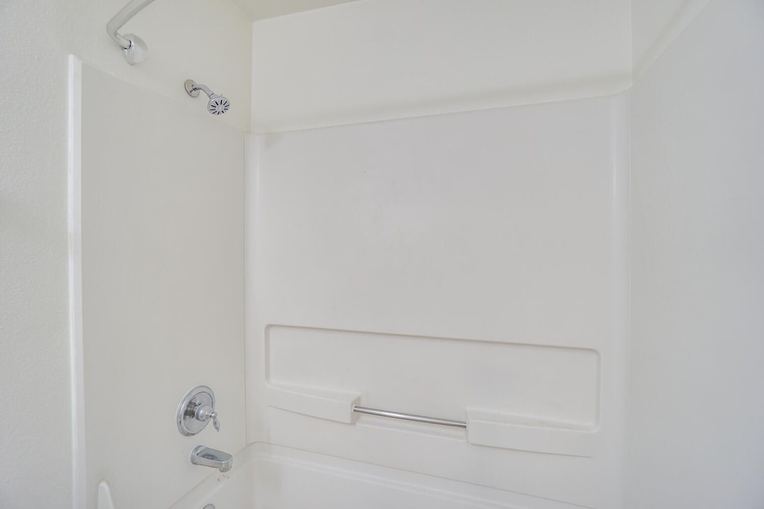 A bathroom with a bathtub , shower , and soap dish.