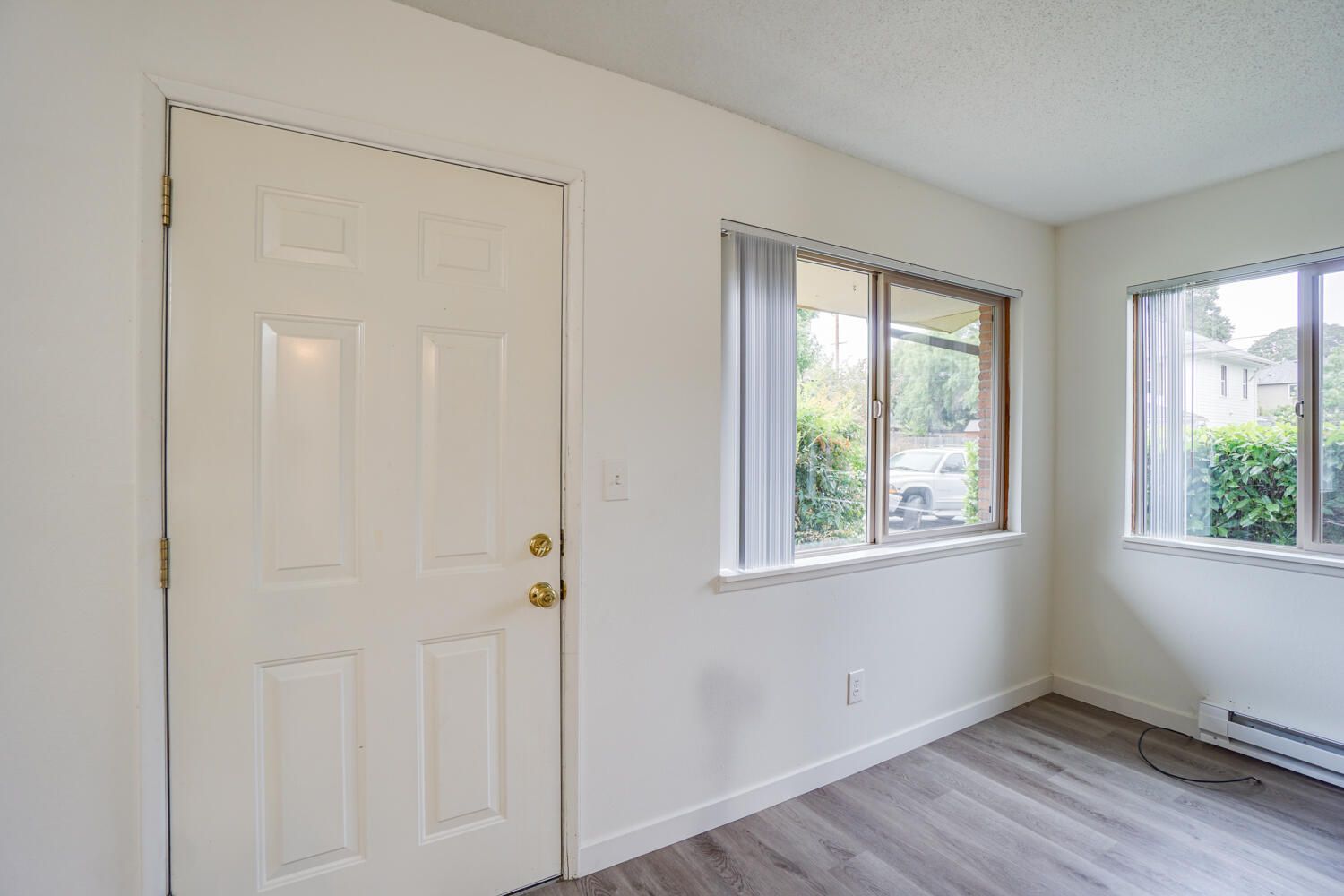 An empty room with a door and two windows.