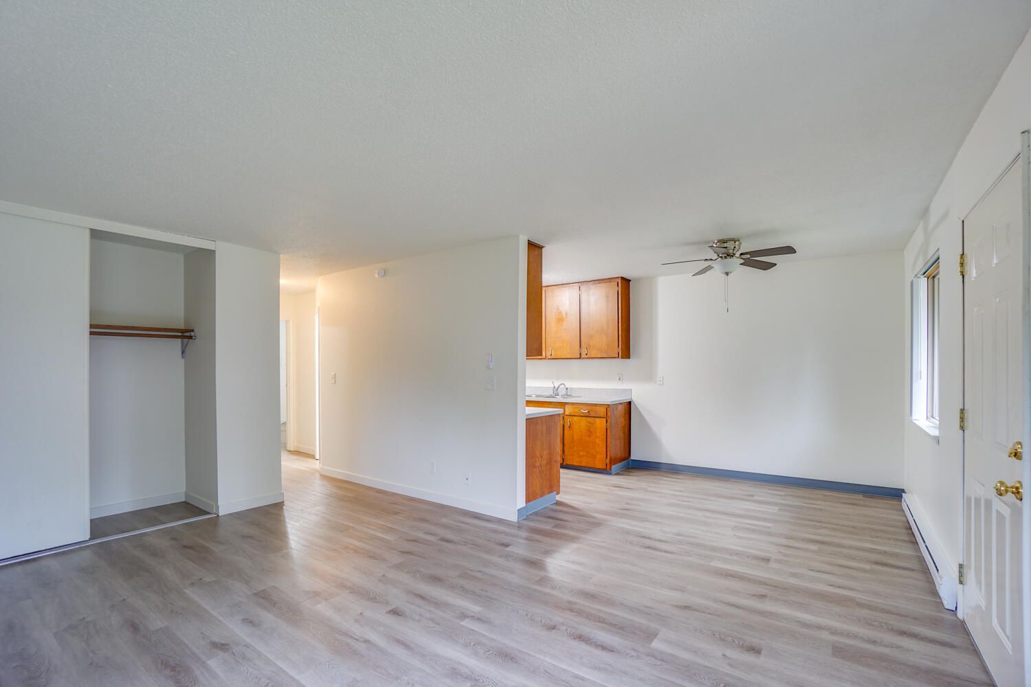 An empty living room with hardwood floors and a ceiling fan.