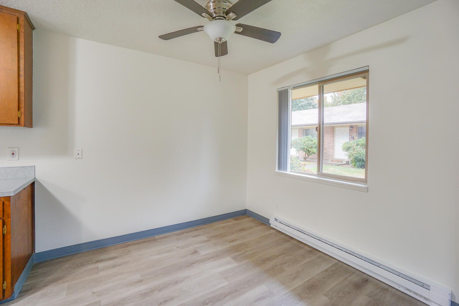 An empty room with a ceiling fan and a window.
