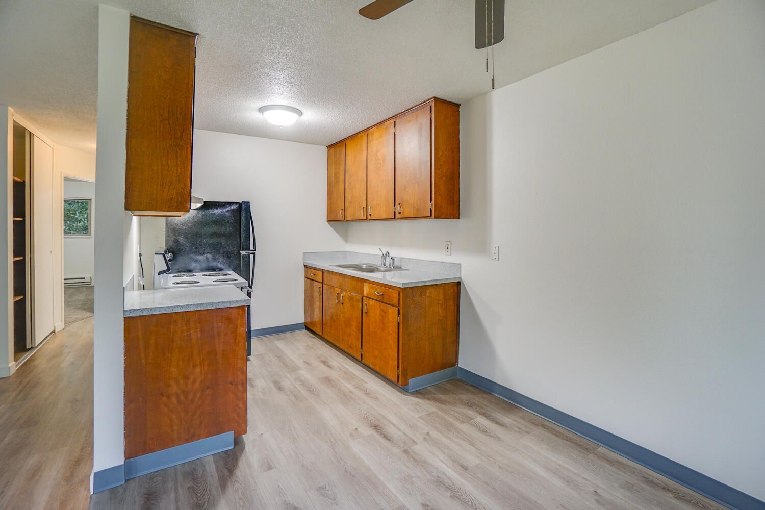 A kitchen with wooden cabinets and a ceiling fan.